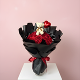 Valentine bouquet of red roses with a teddy bear and heart-shaped balloon on a pink background