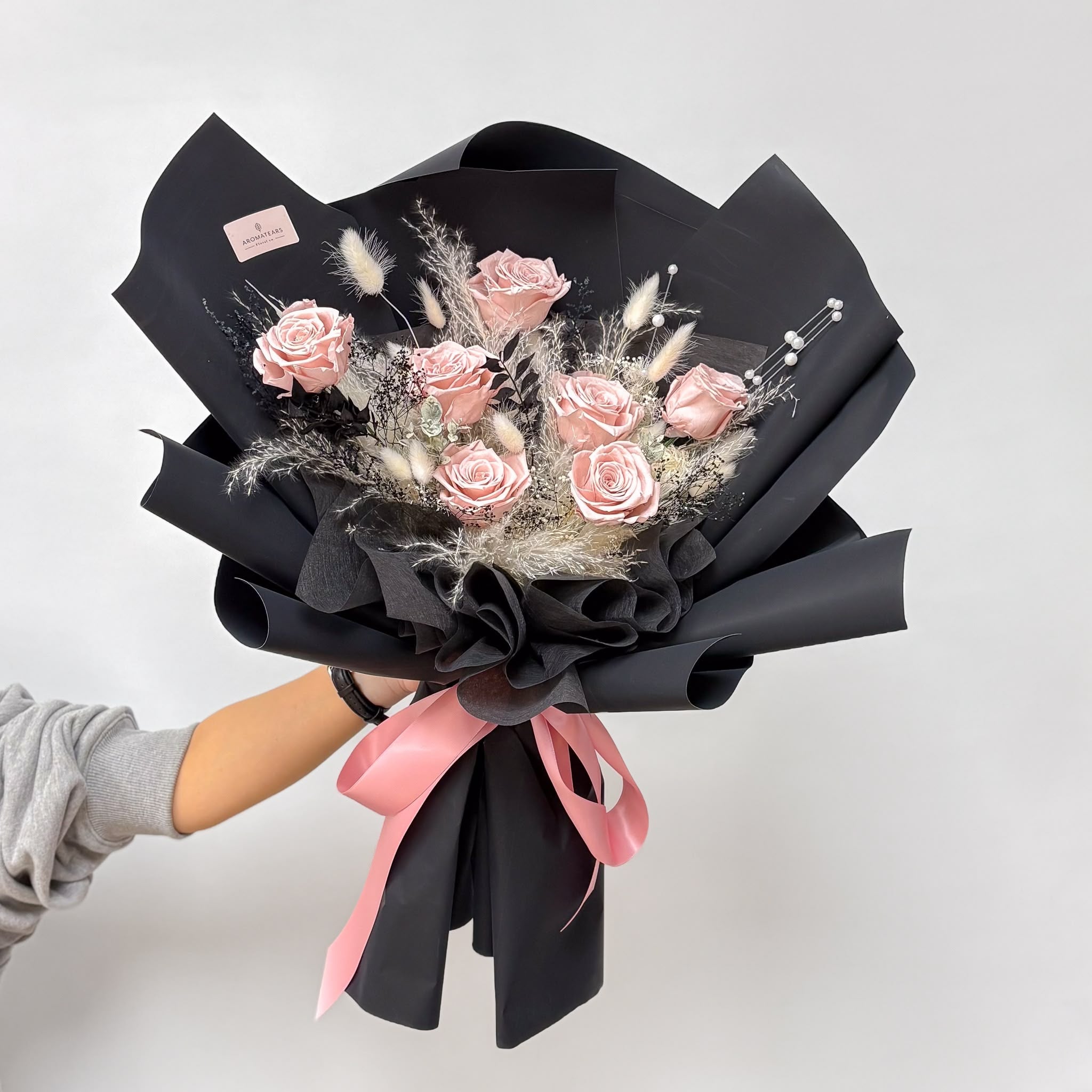 Hand holding the elegant Designer's Choice Nude Pink Preserved Rose Bouquet, a thoughtful and long-lasting flower gift for any special occasion.