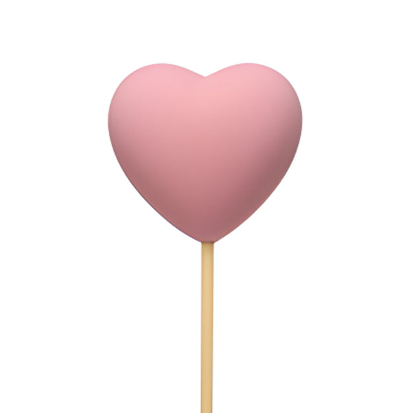 Pink heart-shaped object on a stick against a white background